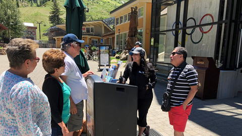 A Mountain Host helping guests in the summertime outside the Aerial Tram. 