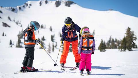 A ski instructor teaching two children at Palisades Tahoe. 