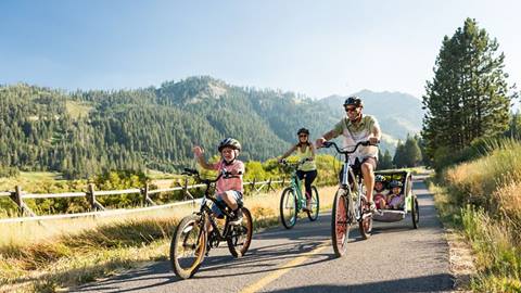 cyclists ride premium e-bikes along a scenic paved path surrounded by trees in north lake tahoe