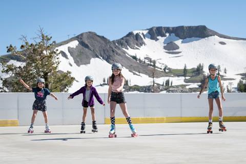 Four girls roller skating at High Camp with a view of the Palisades in the back