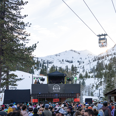 KT Bass Bar with a crowd of people and the Funitel going across with snow capped mountains