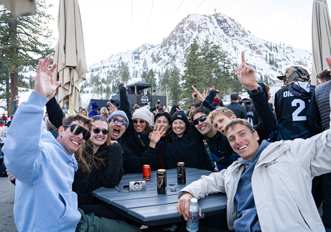 Group of friends smiling with their drinks and hands up at KT Base Bar