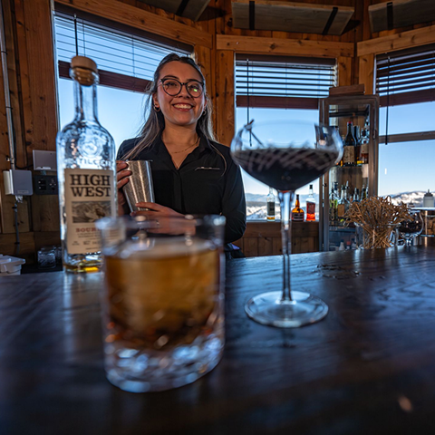Bartender smiling at Alexander's with two whiskey drinks from High West