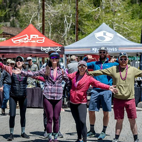 Group of friends smiling with arms out in front of a booth at Made in Tahoe