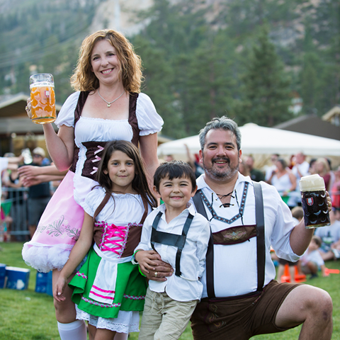 Family smiling in lederhosens and dirndls during Oktoberfest