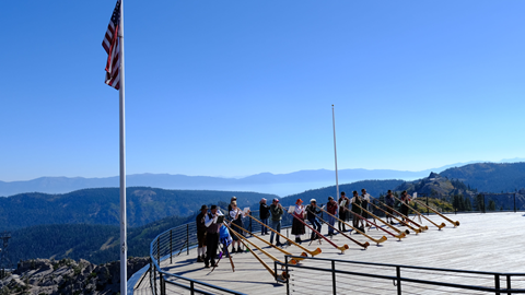 Sierra Alphorn players playing Alphorns at the top of High Camp at Palisades Tahoe