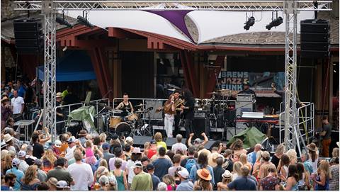A singer on stage at the Blues Jazz and Funk festival, surrounded by a large crowd of people.