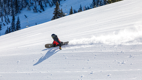 Snowboarder carving groomers