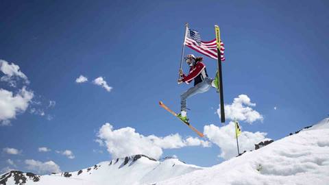 A skier doing a spread eagle with an American flag.
