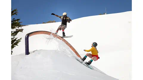 Spring skiing shot of two snowboarders playing in the park.. 