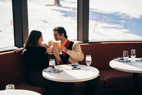 Couple holding drinks to cheers and smiling at Apex Lounge