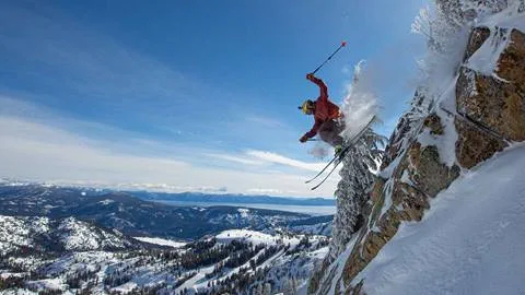 A skier hucks a cliff at Palisades with a view of Lake Tahoe in the background.