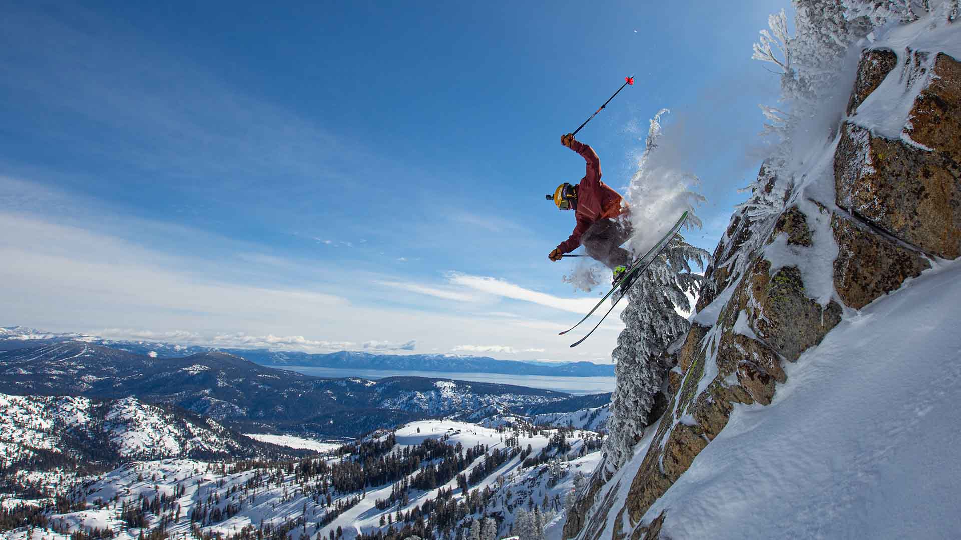 A skier hucks a cliff at Palisades with a view of Lake Tahoe in the background.
