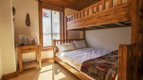 Rustic wooden bunkbeds with a mountain view in The Village at Palisades Tahoe Hotel.