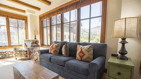 A stunning living area with full mountain views in The Village at Palisades Tahoe Hotel.
