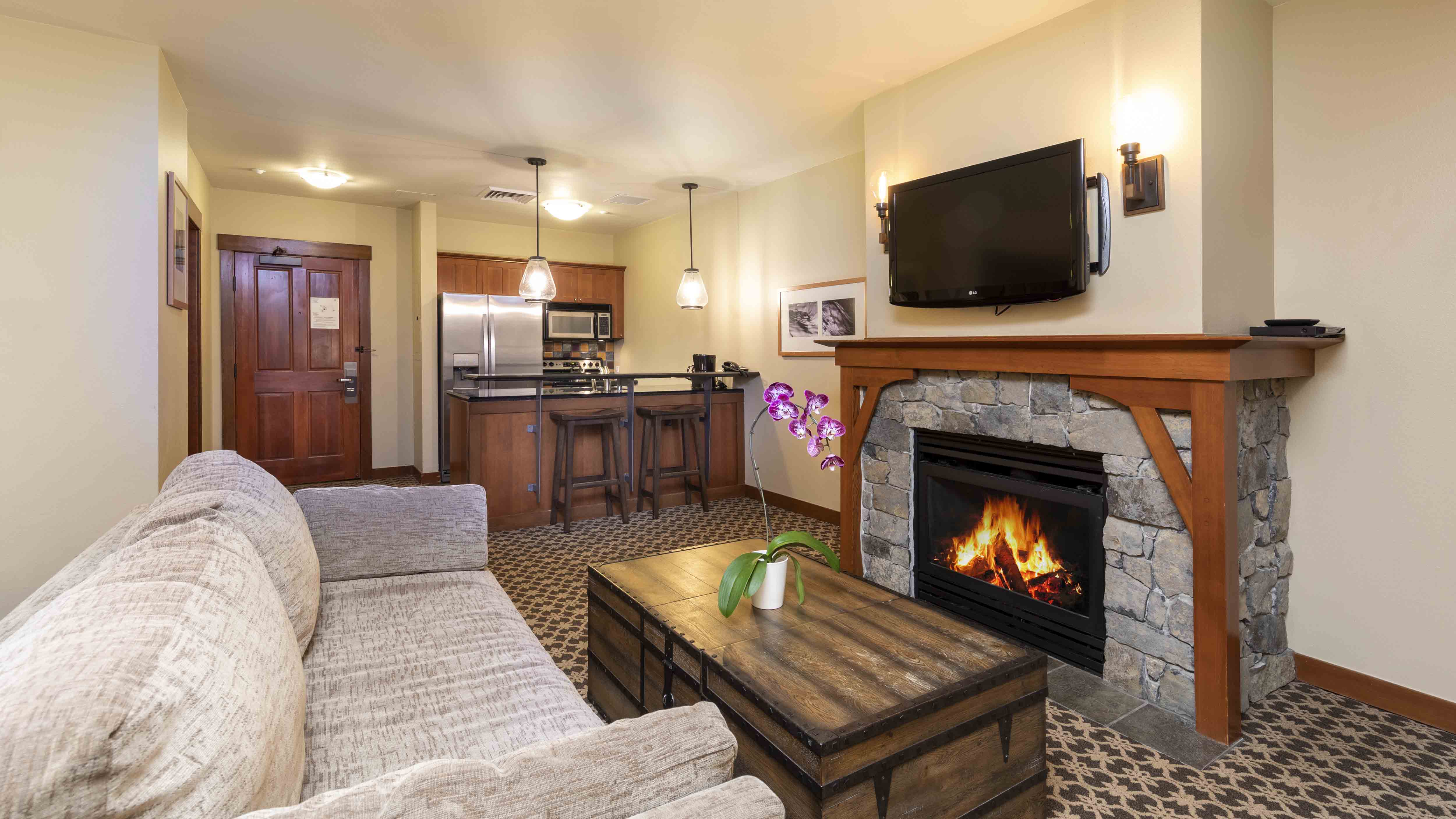 A Studio Room in The Village at Palisades Tahoe shows a seating area and kitchen.