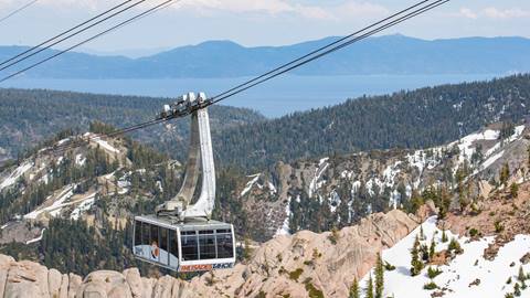 Palisades Tahoe Aerial Tram in May rising above granite rocks with views of Lake Tahoe