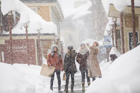 A group of young women marvel at the Palisades Village winter wonderland with shopping bags in hand. 