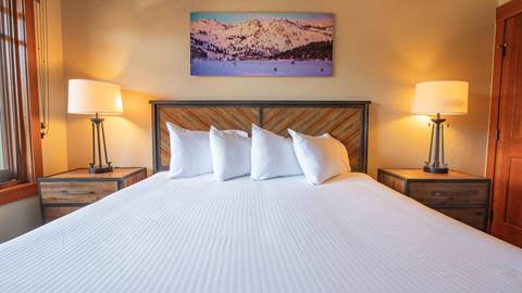 A freshly made bed under natural sunlight in a 1 Bedroom Suite in The Village at Palisades Tahoe.