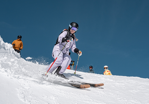 Gal in purple ski suit skiing during a Women of Winter clinic on a groomer