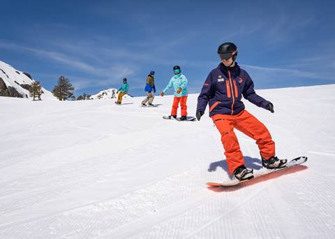 Snowboard instructor leads group down a run