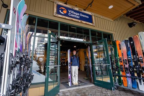 Employee standing with demo skis outside The Village Demo Center