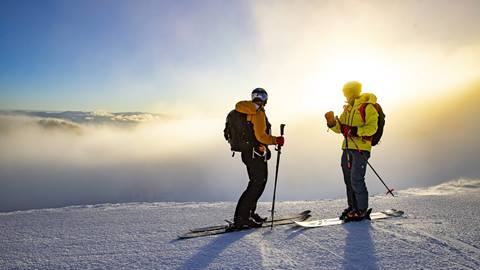 Skiers standing in front of sunset