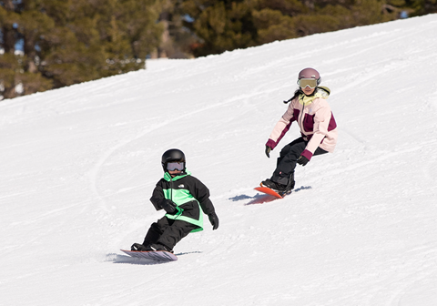 Two kids smiling on groomer in bright jackets