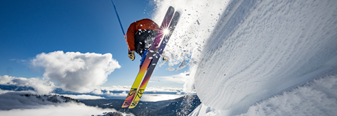 A skier leaps off a cornice in the springtime.