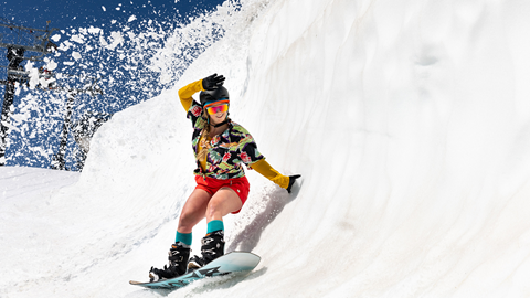 Woman rides slushy halfpipe on snowboard.
