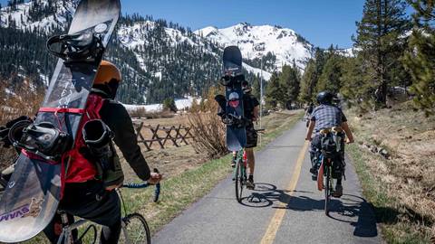 Snowboarders bike to Palisades Tahoe in the spring.