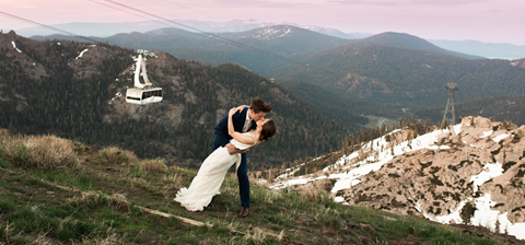 Bride and groom kissing with a scenic view of High Camp, sunset, and Aerial Tram