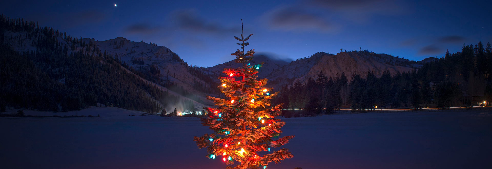 Christmas Tree lit up at night in Palisades Tahoe with mountains in the background