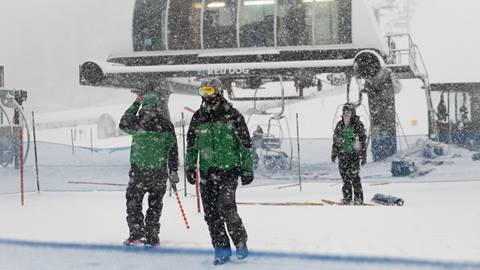 Lift operators in front of the Red Dog chairlift on a snowy day at Palisades Tahoe