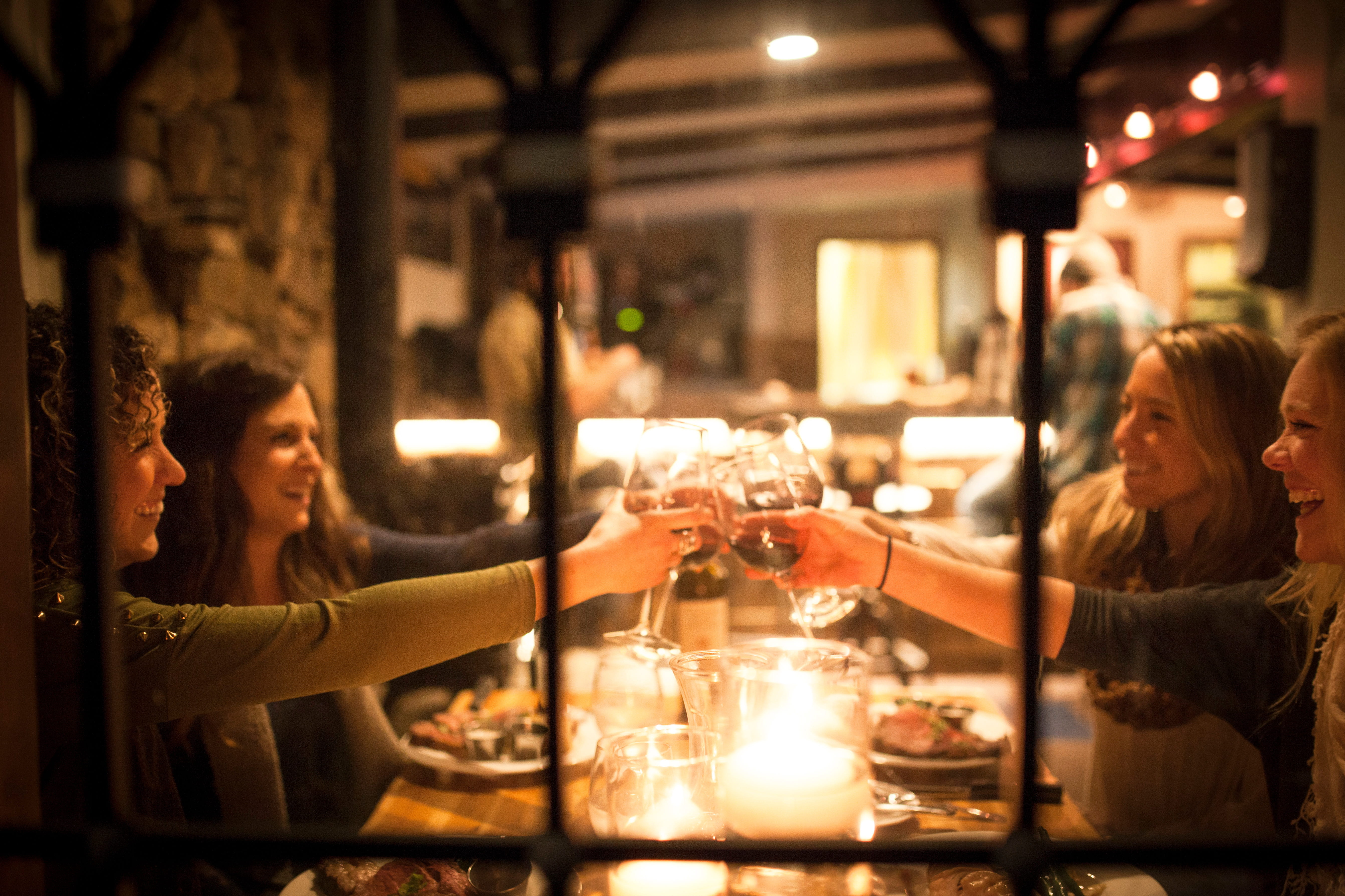 A group of smiling women holds up wine glasses inside the Chalet at Alpine Meadows