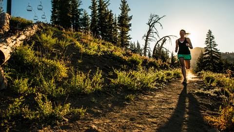 A trail runner runs on a path on a mountain at Palisades Tahoe. 