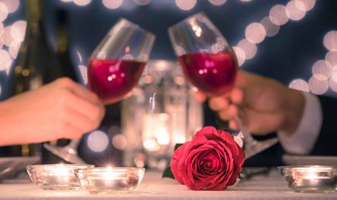 A couple places their glasses of wine together for a cheers on Valentine's Day.