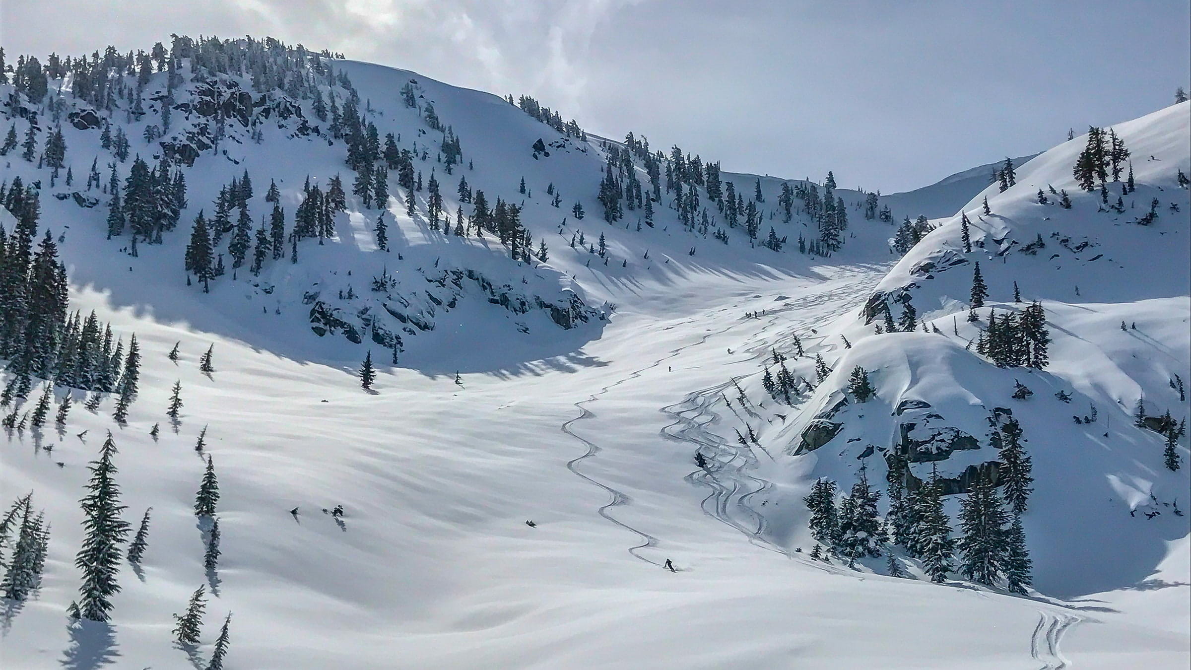 A backcountry skier in a wide open bowl with Alpenglow Expeditions based out of Palisades Tahoe