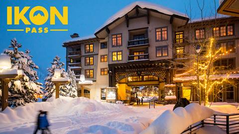 The exterior of The Village at Palisades Tahoe lodging during a snowy winter with the Ikon Pass logo