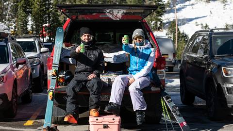 Two people tailgating at their car in preferred parking at Alpine Meadows
