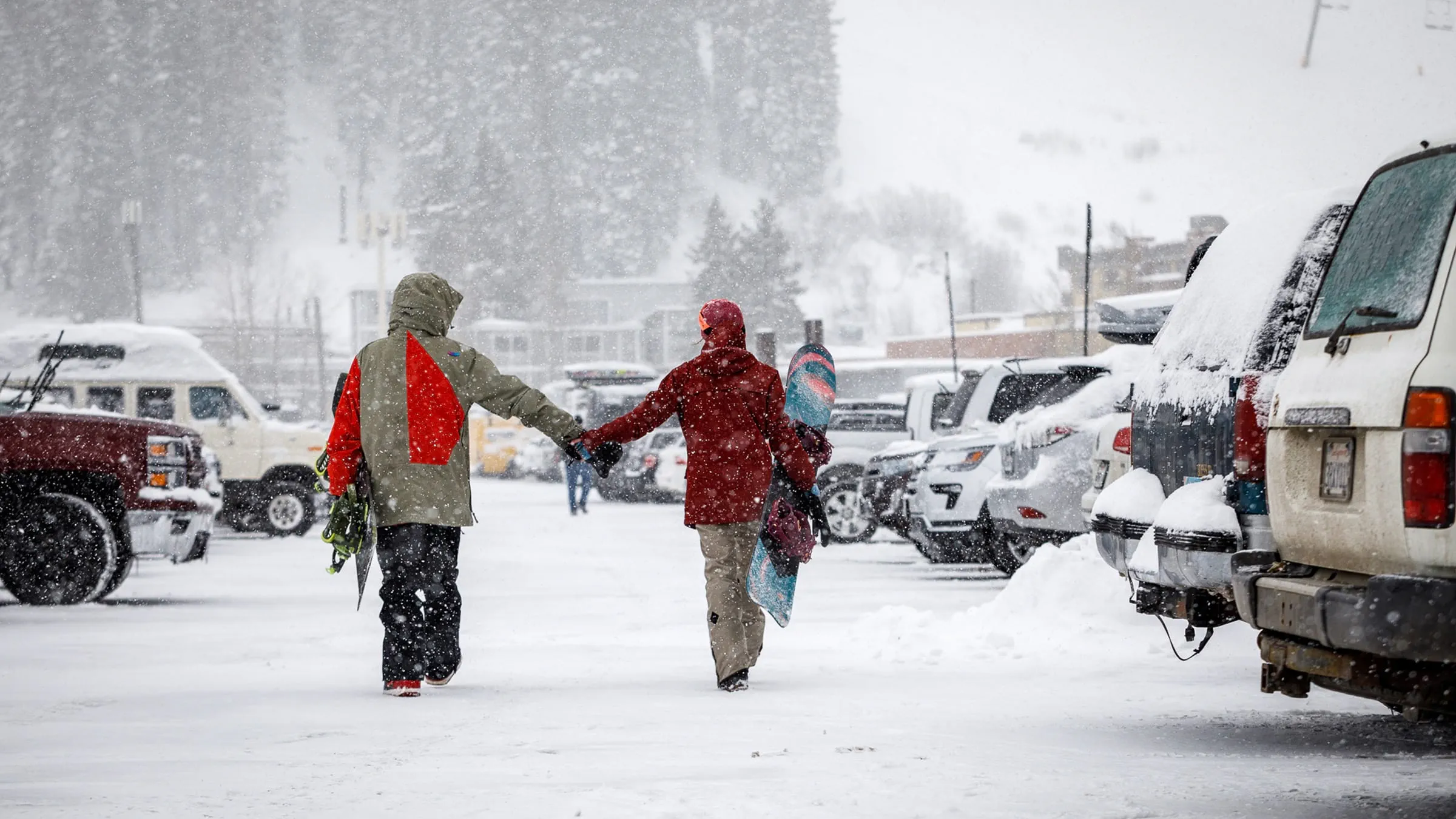 A couple walks through the snowy parking lot at Palisades Tahoe ski resort. 