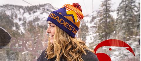 Young woman wearing a Palisades Tahoe beanie smiles and looks off into the distance.