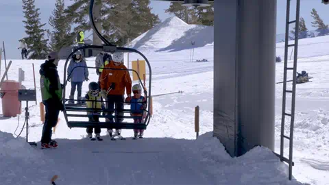 Palisades Tahoe staff help two little kids get on a chairlift.