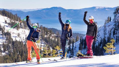 Three skiers wearing masks at Alpine Meadows with Lake Tahoe in the background