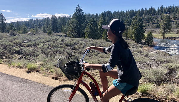 A girl rides her bike in summer along the Legacy Trail in Truckee, CA