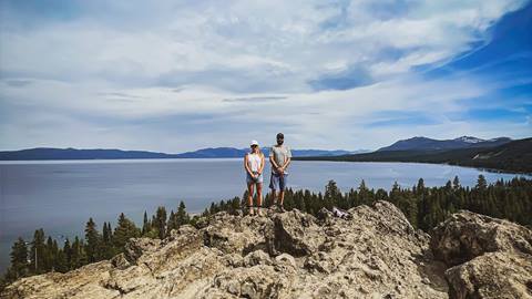Two hikers stand at the top of the popular Eagle Rock Trail with Lake Tahoe in the background