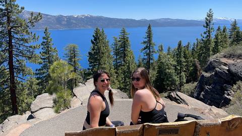 Two women sit at a bench overlook Lake Tahoe at the top of the Stateline Lookout Trail in Nevada