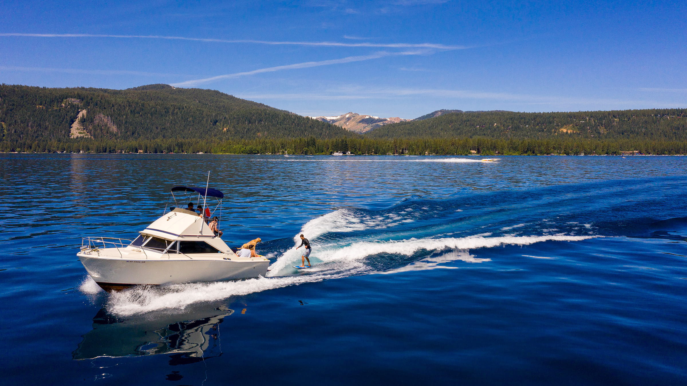 Group of friends wake surfing off a boat in Lake Tahoe during summer
