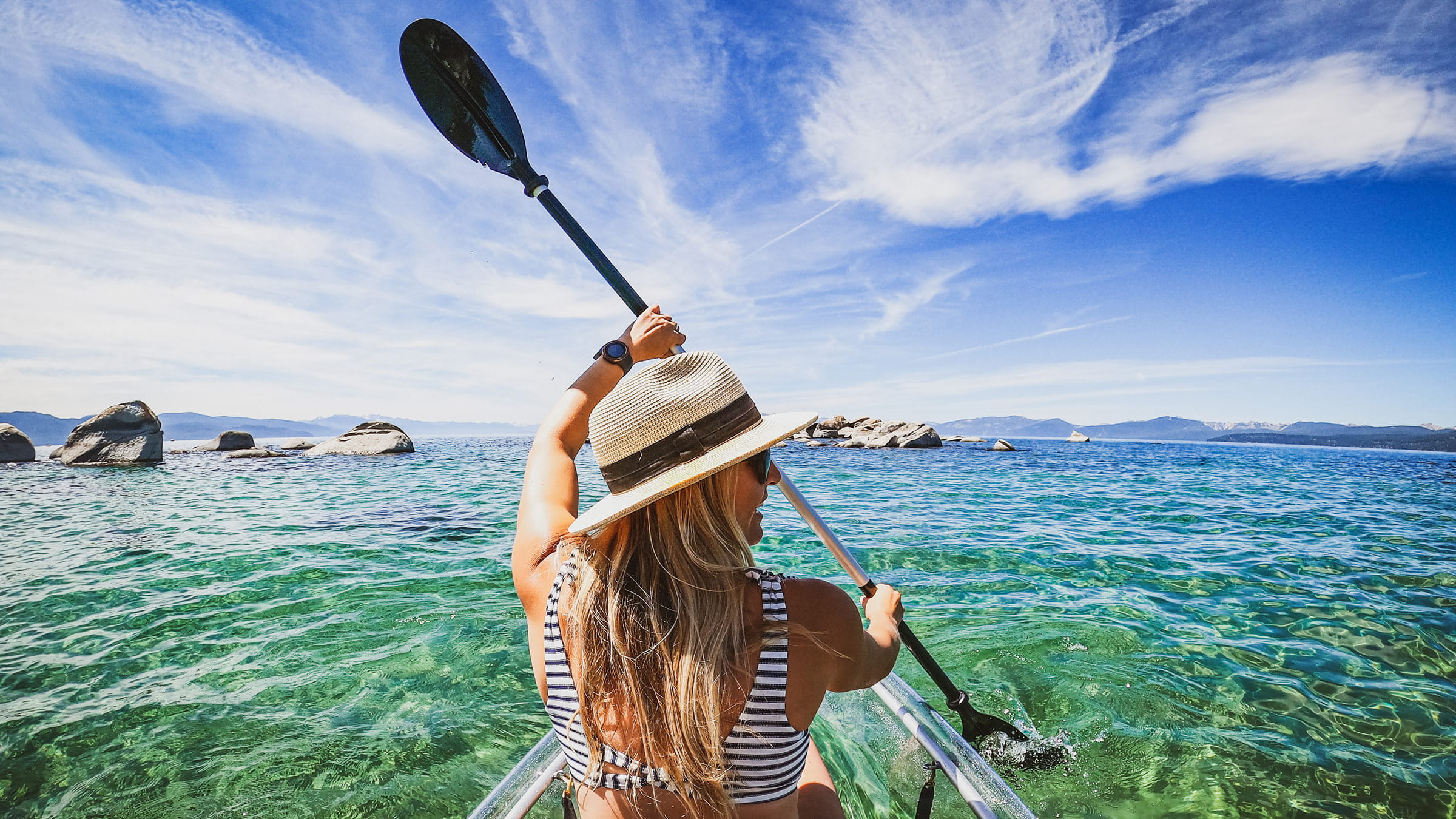 Amie Engerbretson paddling a clear kayak through the clear blue waters of Lake Tahoe's East Shore