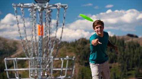 A guy throwing a disc for disc golf at High Camp